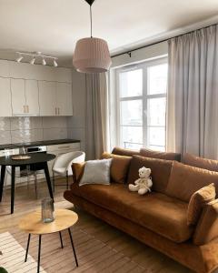 uma sala de estar com um sofá castanho com um urso de peluche em Apartament Zoja em Elblag