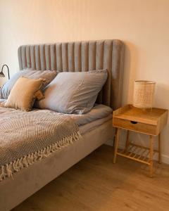 uma cama com almofadas e uma mesa de madeira em Apartament Zoja em Elblag