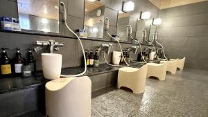 uma casa de banho com uma fila de lavatórios e espelhos em Capsule Hotel Topos Sendai Station Nishiguchi em Sendai