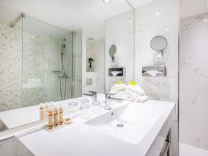 a white bathroom with a sink and a mirror at Hotel Nice Riviera in Nice