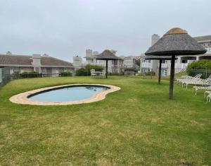 uma piscina num quintal com cadeiras e um guarda-sol em VIlla for Family and Golf em Mossel Bay