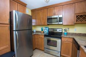a kitchen with wooden cabinets and a stainless steel refrigerator at Island Wind Unit 303 in Fort Walton Beach