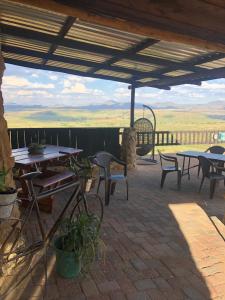 un patio con tavoli, sedie e vista di Uitzicht Private Nature Reserve and Lodge a Fouriesburg