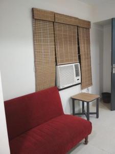 a living room with a red couch and a microwave at Sri Abbirami Lodge in Kumbakonam +17 photos