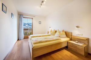 a bedroom with a bed and a window at Urlaub auf dem Bauernhof Hallerhof in Villandro