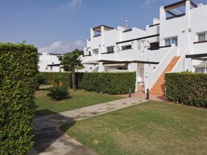 Lovely 3 Bedroom Apartment on Golf Resort في ألاما دي مرسية: اطلالة على مبنى ابيض مع ساحة