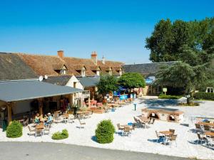 an outdoor patio with tables and chairs in front of a building at Camping 4* 3 CH 2 SDB- Lave linge- Lave vaisselle in Onzain