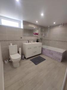 uma casa de banho com um WC, um lavatório e uma banheira em Appartement 100m2, indépendant dans notre maison em Garennes-sur-Eure