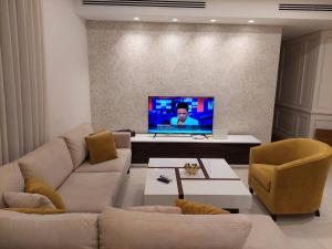 a living room with a couch and a tv at Exquisite Modern 2-bedroom Rental Unit in Amman