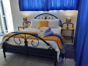 1 dormitorio con 1 cama grande y cortinas azules en 13th Avenue Guesthouse Benoni en Benoni