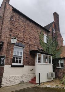 un edificio de ladrillo con una puerta blanca y hiedra en The Fox en Much Wenlock