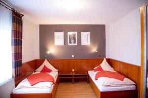 a room with two beds with red pillows at Kleines Hotel Westhus in Dörpen