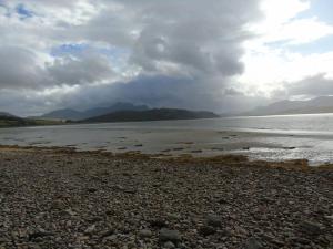 un gran cuerpo de agua con una playa rocosa en Spectacular Highland Cottage Overlooking the Sea en Tongue