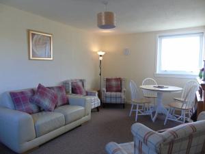 sala de estar con sofá, mesa y sillas en Spectacular Highland Cottage Overlooking the Sea en Tongue