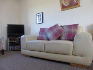 sala de estar con sofá y TV en Spectacular Highland Cottage Overlooking the Sea en Tongue