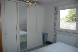 - une chambre avec une armoire blanche et une fenêtre dans l'établissement Haus Burmeister, à Tinnum