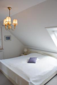 a large white bed with a purple pillow on it at Haus Burmeister in Tinnum