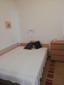 a bedroom with a white bed and a dresser at Udvari-ház in Balatonudvari