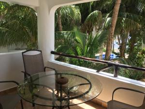 a glass table and chairs in a room with palm trees at Casa 5 Palmas in Puerto Morelos