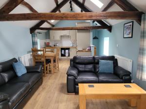 Llanddeiniol的住宿－The Granary，客厅配有黑色真皮沙发和桌子