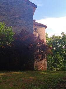 Les granges de l abbaye في Ginals: مبنى حجري قديم في حقل به اشجار