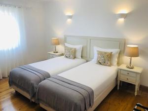 two beds in a bedroom with two lamps on tables at Guarda Rios in Vila Nova de Milfontes