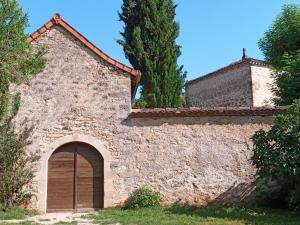 un antiguo edificio de piedra con una puerta y árboles en Les granges de l abbaye en Ginals