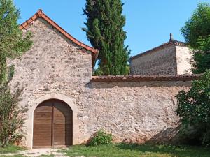 an old stone building with a door and trees at Les granges de l abbaye in Ginals