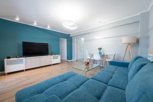 ein Wohnzimmer mit einem blauen Sofa und einem TV in der Unterkunft Central Chic Otopeni - Self Check-in, Netflix, HBO MAX in Otopeni