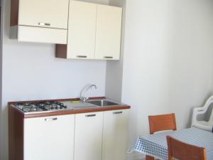a kitchen with white cabinets and a sink and a table at Hotel Isola Rossa in Bosa