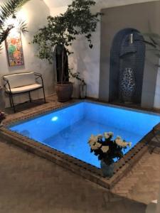 une piscine bleue dans une pièce avec un banc et une plante dans l'établissement Riad SASHA, à Marrakech