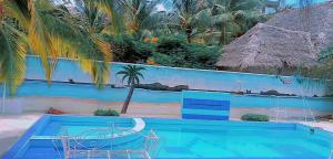 a blue swimming pool with a palm tree and a fence at Nyumba Tulivu in Watamu