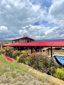 a building with a red roof next to a pool at Hospedaje Villa de piedra in Tinjacá