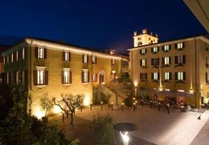 duży budynek z wieżą zegarową w nocy w obiekcie Hotel Alla Torre w mieście Garda