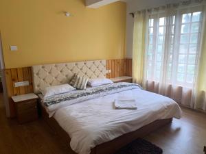 a bedroom with a large bed with a large window at NOLINA BOUTIQUE HOMESTAY in Namchi