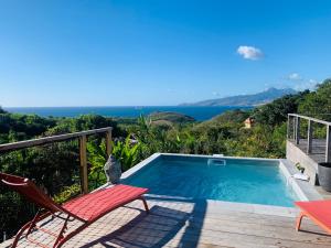 einen Pool mit einer Terrasse, Stühlen und Meerblick in der Unterkunft Villa Fresh&Cosy Trois-Ilets 3 étoiles in Les Trois-Îlets