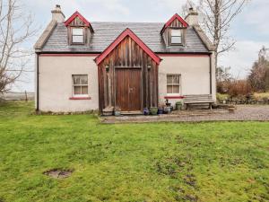 an old house with a bench in front of it at Bogindour Cottage in Muir of Ord
