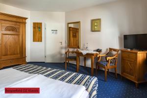 a hotel room with a bed and a desk and a tv at Hotel & Restaurant Villa Ulmenhof in Bredstedt