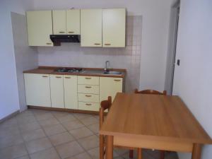 cocina con armarios blancos y mesa de madera en Agriturismo Specchiarussa, en Morciano di Leuca