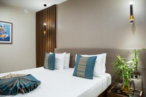 ein Schlafzimmer mit einem großen weißen Bett mit blauen Kissen in der Unterkunft Le Ndiambour Hôtel et Résidence in Dakar