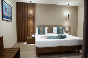 una camera da letto con un grande letto con lenzuola bianche e cuscini blu di Le Ndiambour Hôtel et Résidence a Dakar