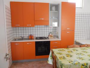 cocina con armarios naranjas, fregadero y cama en Agriturismo Specchiarussa, en Morciano di Leuca