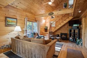 a living room with a large couch and a staircase at Log Home Retreat at Lake Winnipesaukee! in Meredith