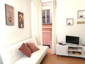 a white living room with a white couch and a tv at Bellagio Centre in Bellagio