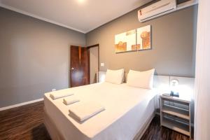 een slaapkamer met een groot wit bed en handdoeken bij Italian Palace Hotel Rede Carlton in Três Corações