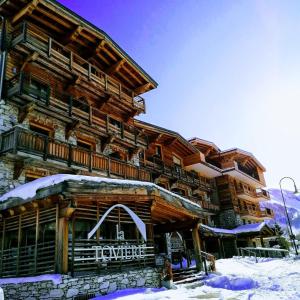 a large wooden building with snow on it at Hotel La Toviere in Val dʼIsère