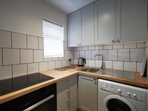 a kitchen with a sink and a washing machine at Surfer's Retreat in Chichester