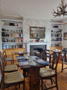 St Vincent Guest House في لينتون: غرفة طعام مع طاولة وكراسي ومدفأة
