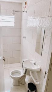 a white bathroom with a toilet and a sink at Pousada alojacampinas in Viracopos