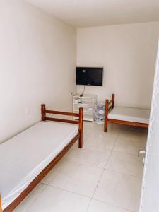 um quarto com 2 camas e uma televisão de ecrã plano em Pousada alojacampinas em Viracopos